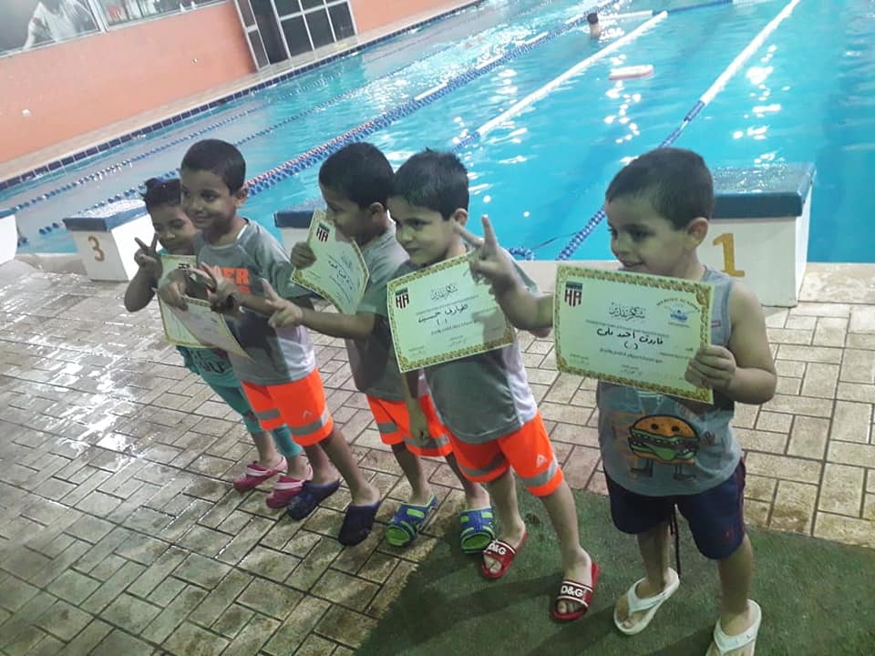 Awarding Al-Sondos children swimming certificates for completing the first level in swimming